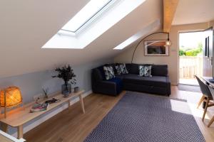 a living room with a black couch and a skylight at Scandi-luxe Studio, with wood fired hot tub in Draycott