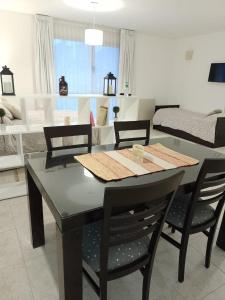 a dining room table with four chairs and a kitchen at Studio Coirón in Comodoro Rivadavia