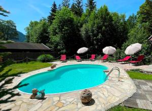 uma piscina com cadeiras e guarda-sóis num quintal em Landhaus Gastager em Ruhpolding