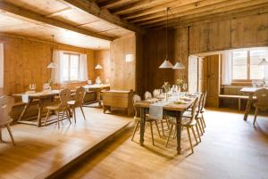uma sala de jantar com paredes e mesas e cadeiras de madeira em Hotel Chasa Chalavaina em Müstair