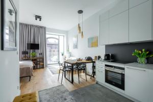kuchnia z białymi szafkami i stołem z krzesłami w obiekcie Apartament Słoneczny - Młyn Maria - Art Apartments we Wrocławiu