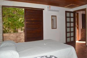 a bedroom with a bed and a large window at Casa do Frá in Morro de São Paulo