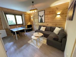 een woonkamer met een bank en een tafel bij Cosy appartement au calme à deux pas du centre in Auron
