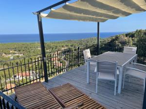 una terraza de madera con mesa, sillas y sombrilla en Casa Grazia e Enrico, en Chia