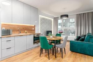 kuchnia i salon ze stołem i zielonymi krzesłami w obiekcie Star4You II Apartments we Wrocławiu