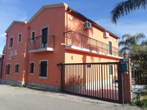 a red and orange house with a black gate at La Casetta B&B in Milazzo