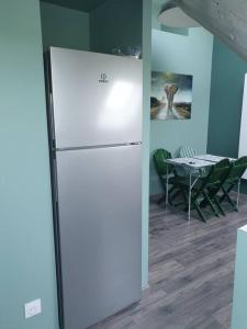 białą lodówkę w pokoju ze stołem w obiekcie Les toits - Audun le Tiche - Appartement 3 chambres w mieście Audun-le-Tiche