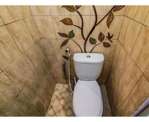 a bathroom with a toilet with a tree on the wall at Kartini Guest House near Alun Alun Probolinggo in Sukobumi