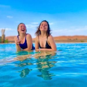 dos mujeres nadando en un cuerpo de agua en Riad Caravasar en Merzouga