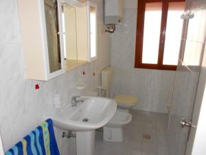 a white bathroom with a sink and a toilet at Sabrina in Rosolina Mare