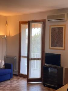 ein Wohnzimmer mit einem TV und einer Glasschiebetür in der Unterkunft Oasi in Desenzano del Garda