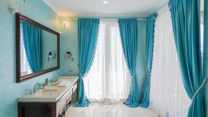 a bathroom with blue curtains and a sink and a mirror at Phoenicia Boutique Hotel - Adults Only in Mamaia Nord