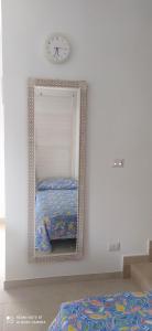 a mirror in a room with a bed and a clock at Villa Francesca Appartamento Meraviglioso in Polignano a Mare