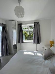 sypialnia z dużym białym łóżkiem przed oknem w obiekcie Dingley Dell - Superb location for Truro in private accommodation w mieście Perranwell