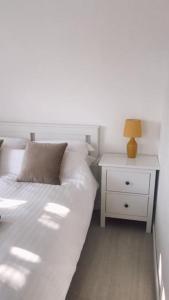 a white bedroom with a bed and a night stand at Dingley Dell - Superb location for Truro in private accommodation in Perranwell