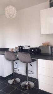 a kitchen with two bar stools in front of a counter at Dingley Dell - Superb location for Truro in private accommodation in Perranwell