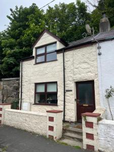 a white stone house with a door and windows at Tan y Marian in Cwm-y-glo