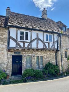 una vecchia casa in pietra con una porta nera di Luxury Cotswolds Cottage optional Hot Tub, Castle Combe a Castle Combe