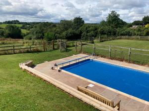 a swimming pool in a yard with a fence at Little Pentre Barn with cosy logburner in Wrexham