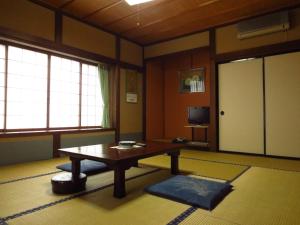 een woonkamer met een tafel en een televisie bij Shitanda in Takayama