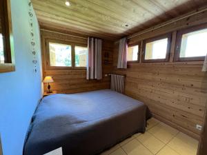 a bedroom with a bed in a wooden cabin at Petit Lutin - Chalet sur les pistes in La Clusaz