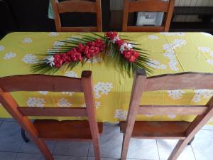 une table jaune avec des fleurs et 2 chaises dans l'établissement A Pueu Village, à Pueu
