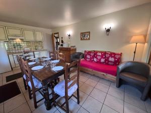 a dining room with a table and a red couch at Petit Lutin - Chalet sur les pistes in La Clusaz