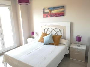 ein Schlafzimmer mit einem großen weißen Bett mit lila Lampen in der Unterkunft Precioso Apartamento Planta Baja Junto a la playa in Isla Canela