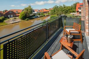 Un balcón con 2 sillas, una mesa y un río en Küsten Suite Ost direkte Wasserlage, 2 Balkone, 90qm, en Greetsiel