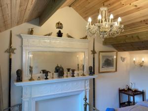 einen Kamin mit einem Spiegel und einem Kronleuchter in der Unterkunft The Gin Palace with pool now open in Wrexham