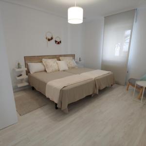 1 dormitorio con 1 cama grande en una habitación blanca en Tu Casina del Norte, en Luanco