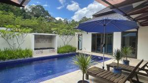 a house with a swimming pool and an umbrella at Charis Pool Villa 2 - 3 bedroom with Private Pool in Bentong