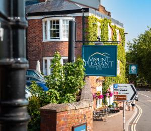 a sign in front of a brick building with a mountain apartment at Mount Pleasant Hotel in Great Malvern