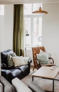 uma sala de estar com um sofá e uma cadeira em Huisje Nummer Tien em Sint-Laureins