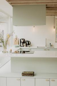 een witte keuken met witte kasten en een wastafel bij Huisje Nummer Tien in Sint-Laureins