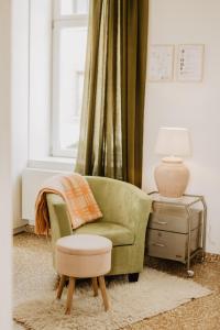 een woonkamer met een groene stoel en een kruk bij Huisje Nummer Tien in Sint-Laureins
