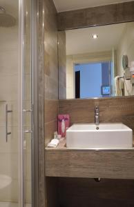 ein Badezimmer mit einem weißen Waschbecken und einem Spiegel in der Unterkunft Best Western Hotel St. Michael in Morbach