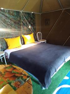 a bed in a tent with yellow pillows and a table at la tente du commandant français 1954 pour nuit insolite in Arrest