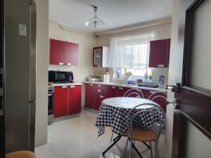 グダニスクにあるOlaf Apartのキッチン(赤いキャビネット、テーブル、テーブルクロス付)