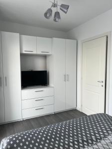 1 dormitorio blanco con 1 cama y TV de pantalla plana en Apartament Otopeni lângă parc, en Otopeni