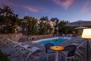 a pool with chairs and a table and an umbrella at Capri Blue Luxury Villa Le Tre Monelle in Anacapri