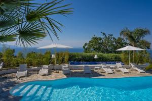 a swimming pool with chairs and umbrellas at Capri Blue Luxury Villa Le Tre Monelle in Anacapri