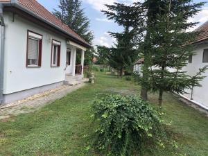 a yard next to a white house with a tree w obiekcie Relax Home/Lazit-Lak w mieście Ebergőc