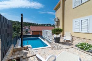 un patio trasero con piscina y una casa en Apartments Kapetan, en Trogir