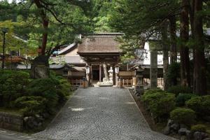 a walkway in front of a building with trees at Koyasan Shukubo Saizenin in Koyasan