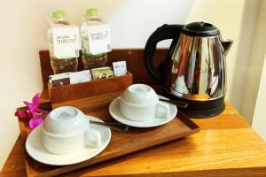 a tea kettle and saucers on a wooden tray at Greenhost Boutique Hotel Prawirotaman in Yogyakarta