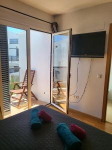 a bedroom with a bed and a flat screen tv at Casa Playa La Fontanilla SOTOLODGE in Conil de la Frontera