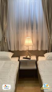 a room with two beds and a table with a lamp at Gabrijel Apartments Makarska 1 in Makarska