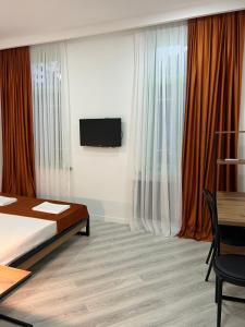 a bedroom with a bed and a tv and curtains at Polifonia Inn Borjomi in Borjomi