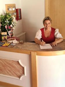 a woman sitting at a counter with a paper at Hotel Alpenhof*** in Kaltenbach